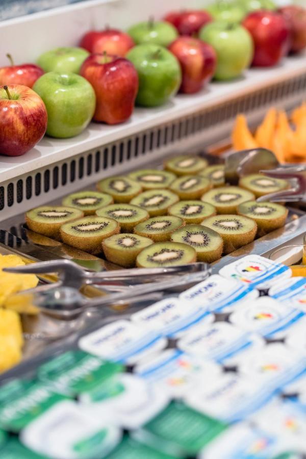 Hotel Le Plaza Bruselas Exterior foto The photo shows a selection of sliced kiwifruit arranged neatly on a metal tray. The slices reveal the green flesh with tiny black seeds in the center. In the background, there are also whole apples, and nearby, there seems to be additional fruit, po