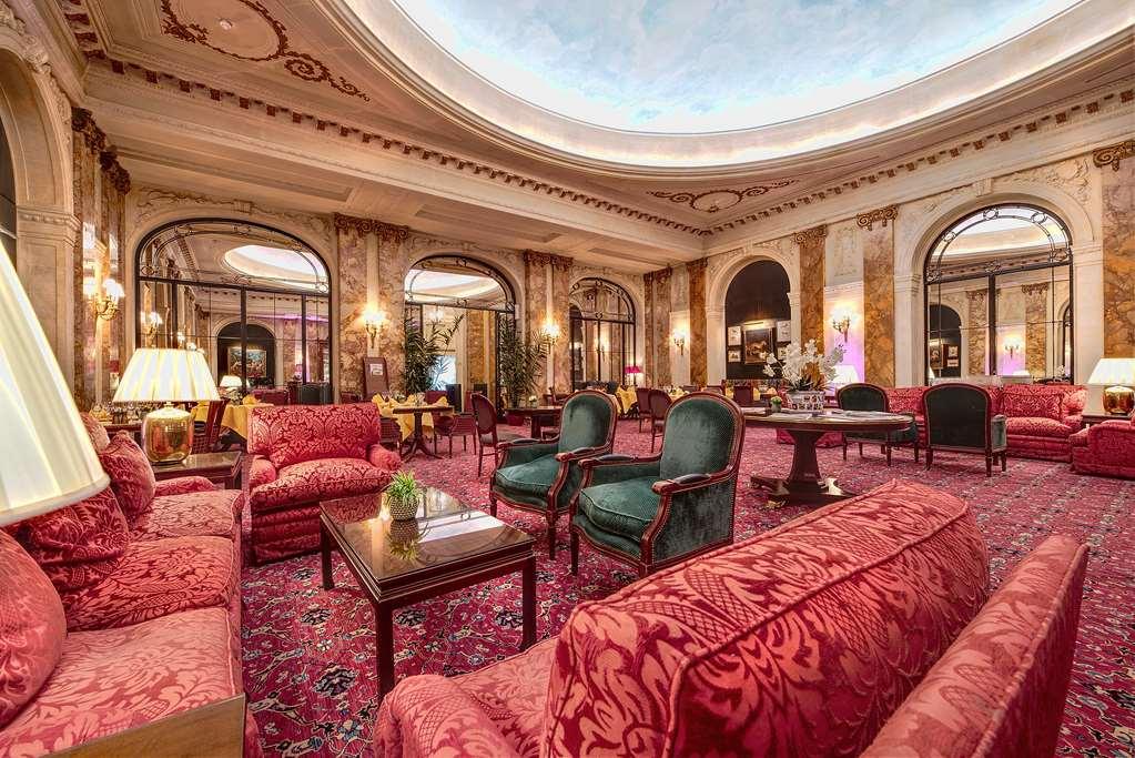 Hotel Le Plaza Bruselas Interior foto The photo shows a luxurious and elegant lounge area, characterized by richly decorated furnishings. There are plush red sofas and armchairs arranged in a cozy manner, complemented by a decorative rug on the floor. The space features warm lighting fro