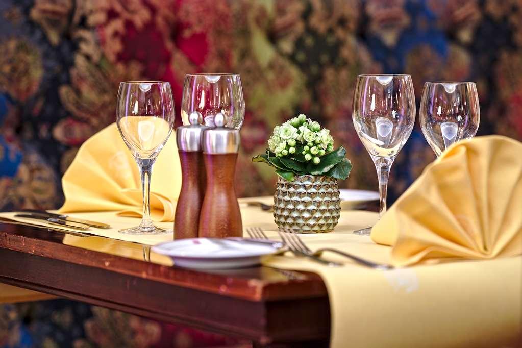 Hotel Le Plaza Bruselas Interior foto The photo shows a restaurant table set for a meal. It features several clear wine glasses positioned elegantly, alongside a small decorative arrangement of flowers in a round vase. There are also two wooden salt and pepper shakers and folded yellow n