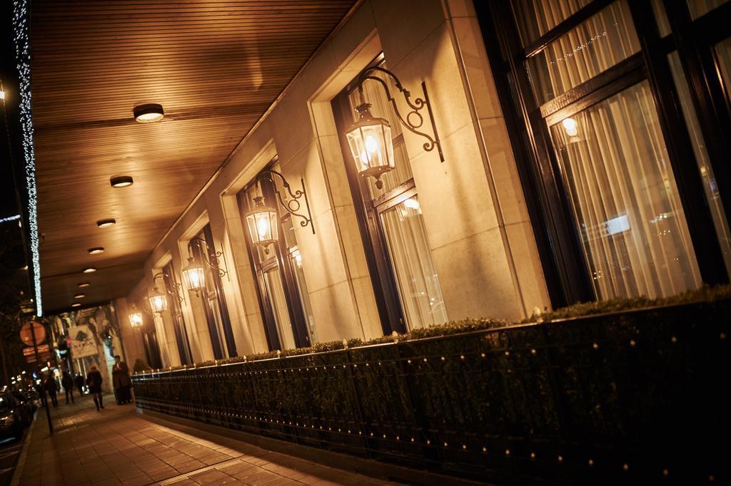 Hotel Le Plaza Bruselas Exterior foto The photo shows a well-lit exterior of a building, featuring a series of windows along a wall. Each window has decorative lanterns mounted beside it, casting a warm glow. The atmosphere appears inviting, possibly indicating a hotel or upscale establi